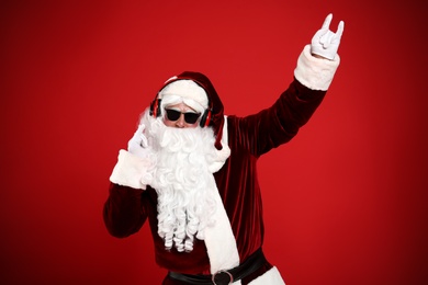Santa Claus with headphones listening to Christmas music on red background
