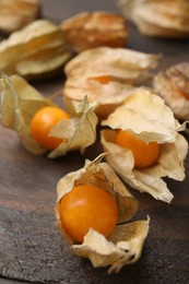 Ripe physalis fruits with calyxes on wooden table, closeup