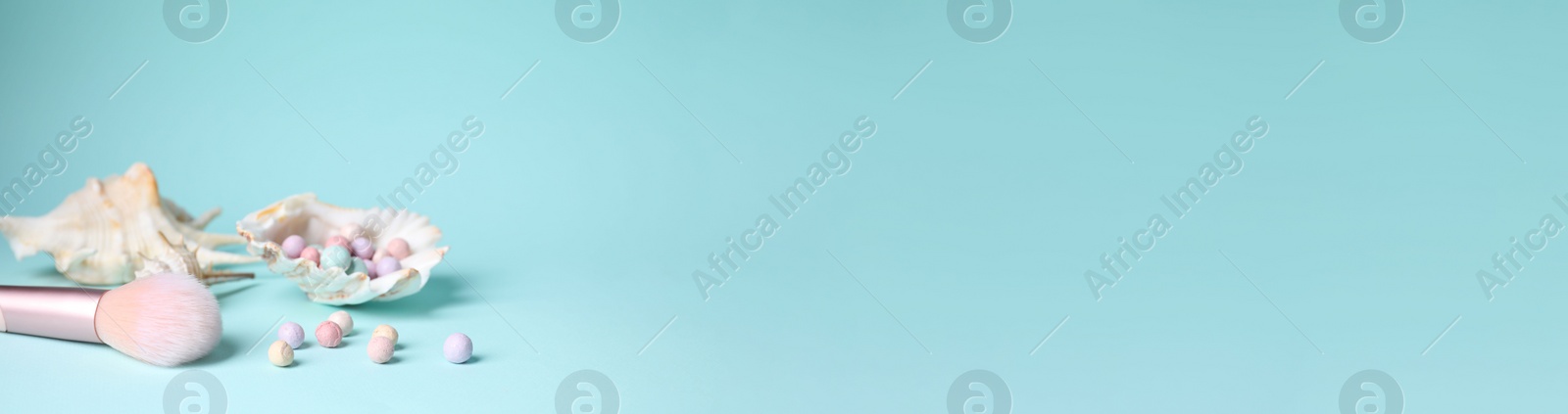 Photo of Powder balls, make up brush and sea shell on light blue background, space for text. Banner design