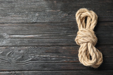 Photo of Bundle of natural hemp rope on wooden background, top view with space for text