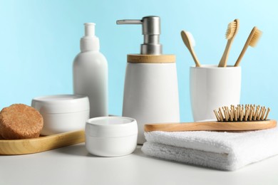 Photo of Different bath accessories on white table against light blue background