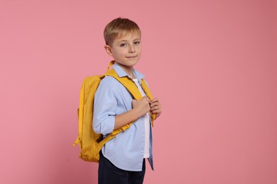 Photo of Happy schoolboy with backpack on pink background, space for text