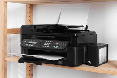 Photo of Modern printer with paper on wooden shelf in home office