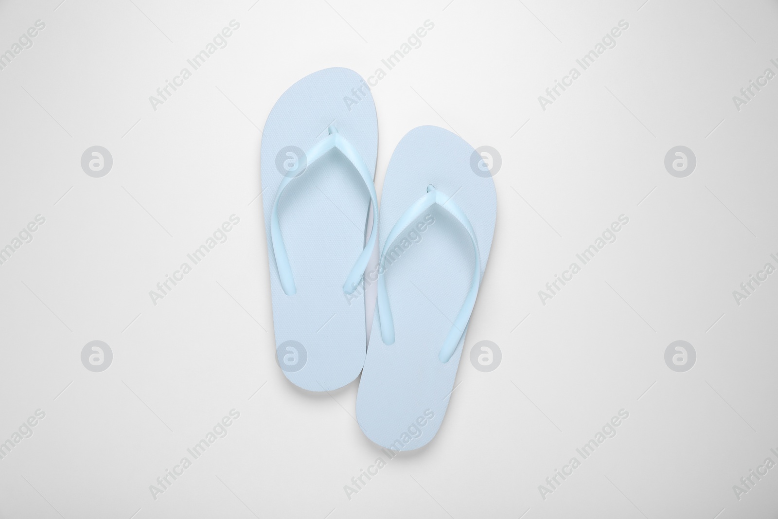 Photo of Light blue flip flops on white background, top view