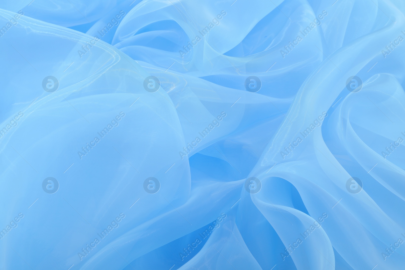 Photo of Beautiful light blue tulle fabric as background, closeup