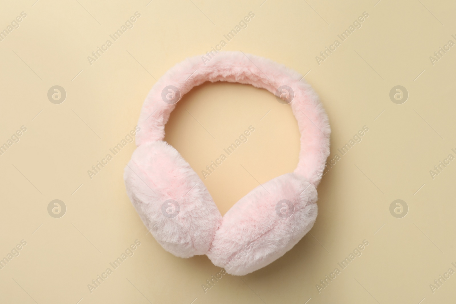 Photo of Stylish warm earmuffs on beige background, top view