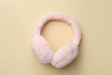 Stylish warm earmuffs on beige background, top view