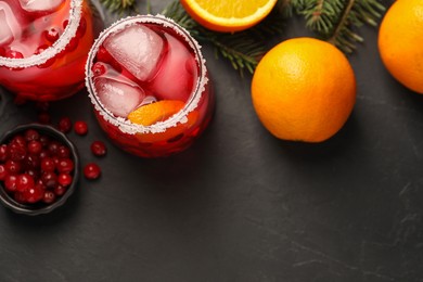 Photo of Tasty cranberry cocktail with ice cubes in glasses on dark gray table, flat lay. Space for text