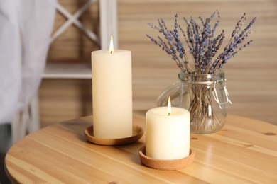 Photo of Burning candles and dried lavender on wooden table indoors