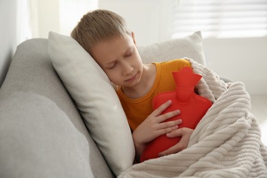 Photo of Ill boy with hot water bottle suffering from cold at home