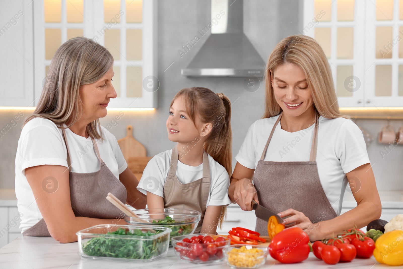 Photo of Three generations. Happy grandmother, her daughter and granddaughter cooking together in kitchen