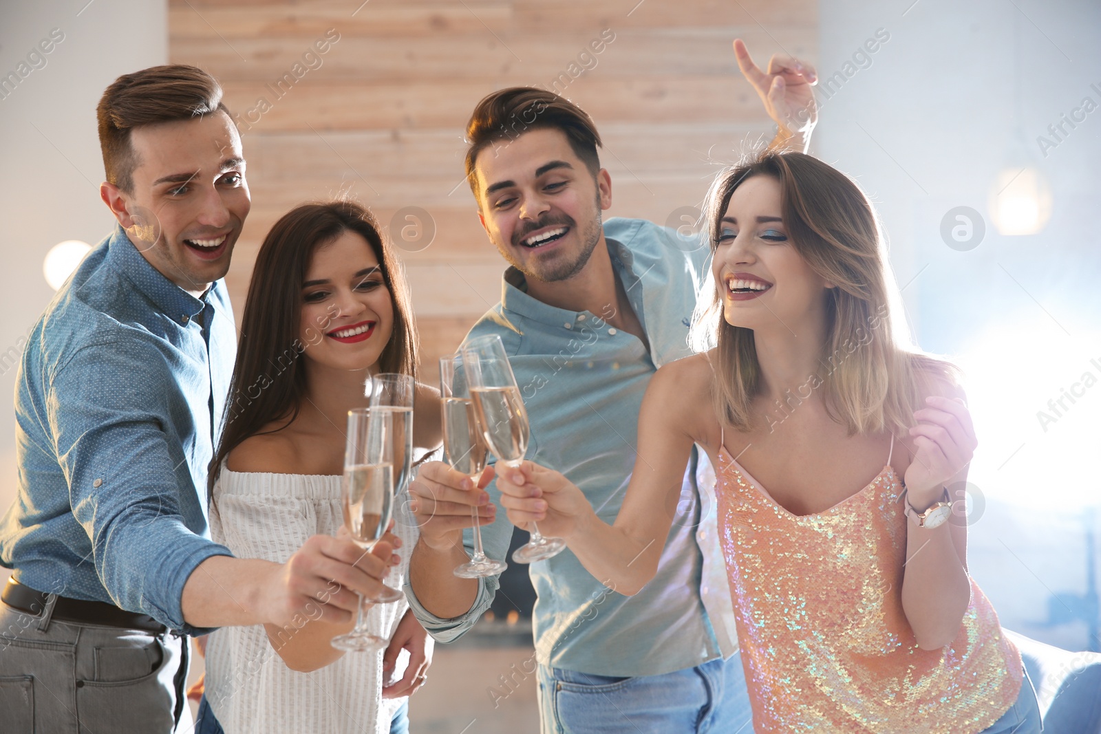 Photo of Friends clinking glasses with champagne at party indoors