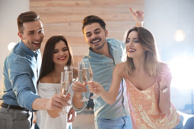 Friends clinking glasses with champagne at party indoors