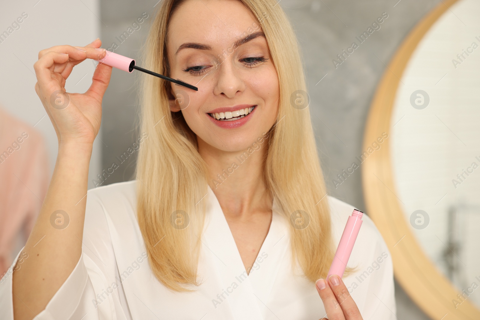 Photo of Beautiful happy woman with mascara in bathroom