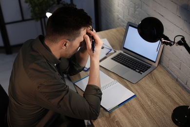 Photo of Overworked man with headache in office