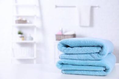 Photo of Stack of fresh towels on table in bathroom. Space for text