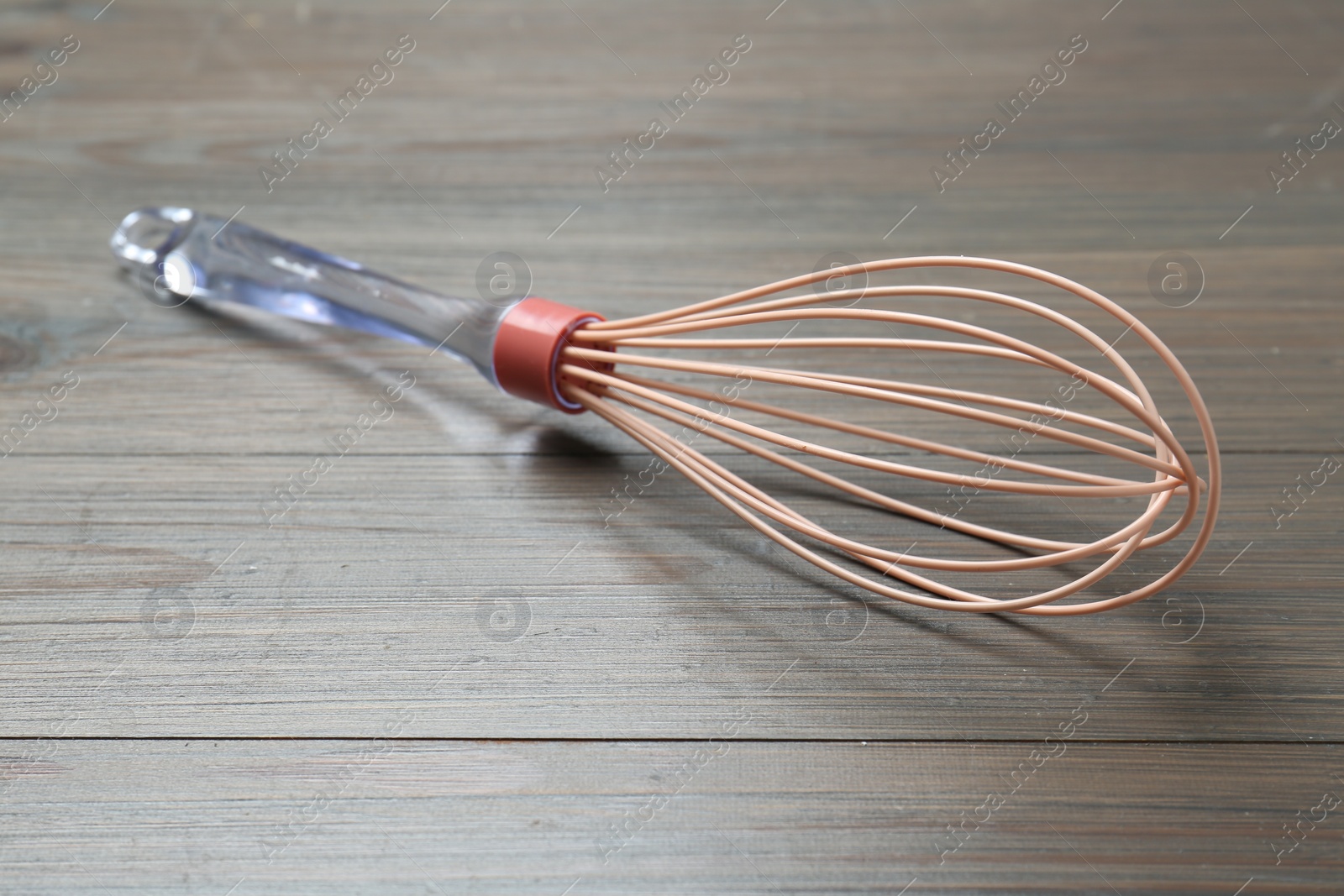 Photo of One whisk on wooden table, closeup. Kitchen tool