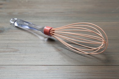Photo of One whisk on wooden table, closeup. Kitchen tool