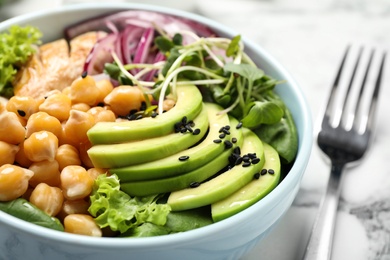 Photo of Delicious avocado salad with chickpea on white marble table, closeup