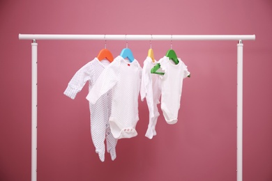 Baby clothes hanging on rack against color background