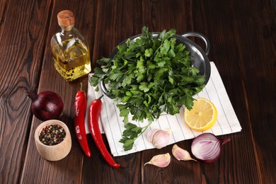 Photo of Colander with fresh parsley, spices and other products on wooden table