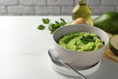 Photo of Delicious guacamole served on white table, space for text