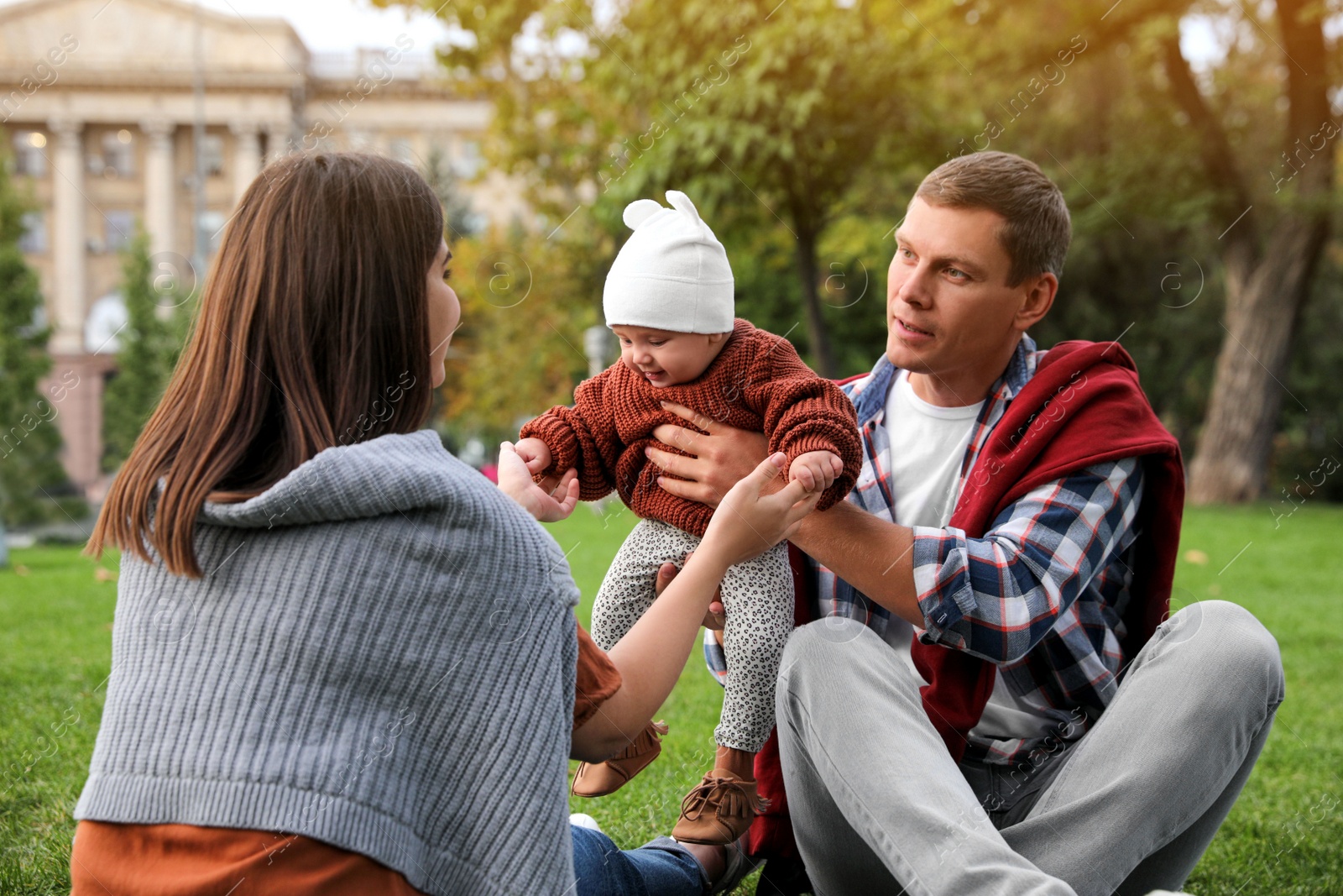 Photo of Happy parents with their adorable baby on green grass in park