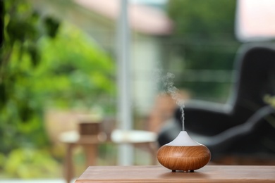 Photo of Aroma oil diffuser lamp on table against blurred background