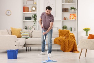 Photo of Spring cleaning. Man with mop washing floor at home