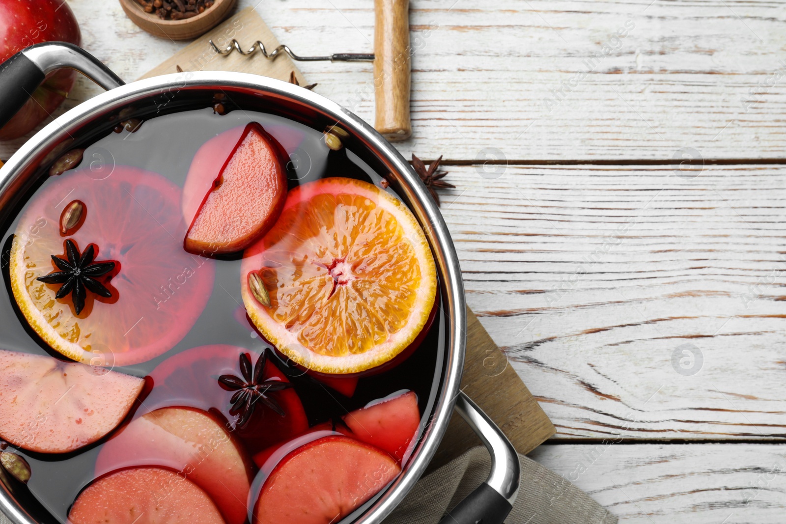 Photo of Delicious mulled wine and ingredients on white wooden table, flat lay. Space for text