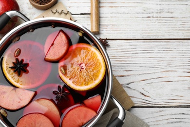Photo of Delicious mulled wine and ingredients on white wooden table, flat lay. Space for text