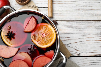 Delicious mulled wine and ingredients on white wooden table, flat lay. Space for text