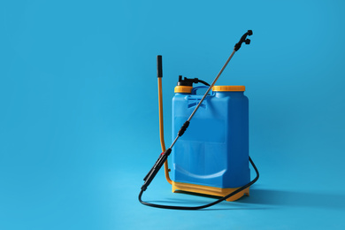Photo of Manual insecticide sprayer on blue background, space for text. Pest control