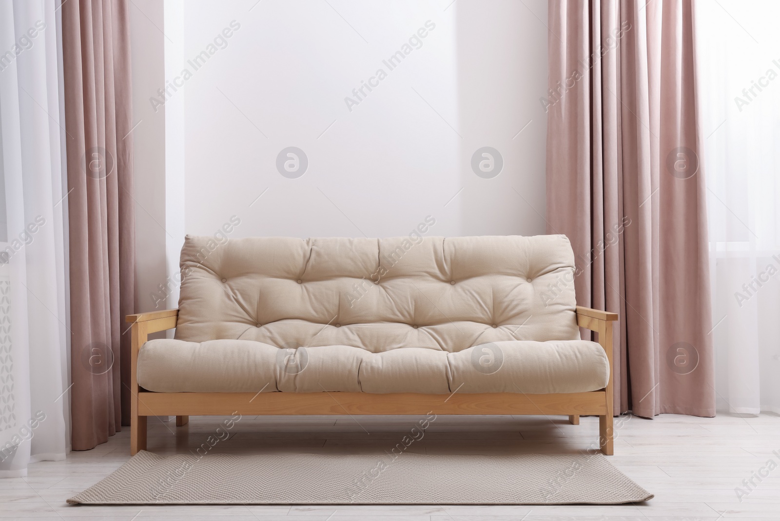 Photo of Comfortable sofa with rug in cozy light room. Interior design