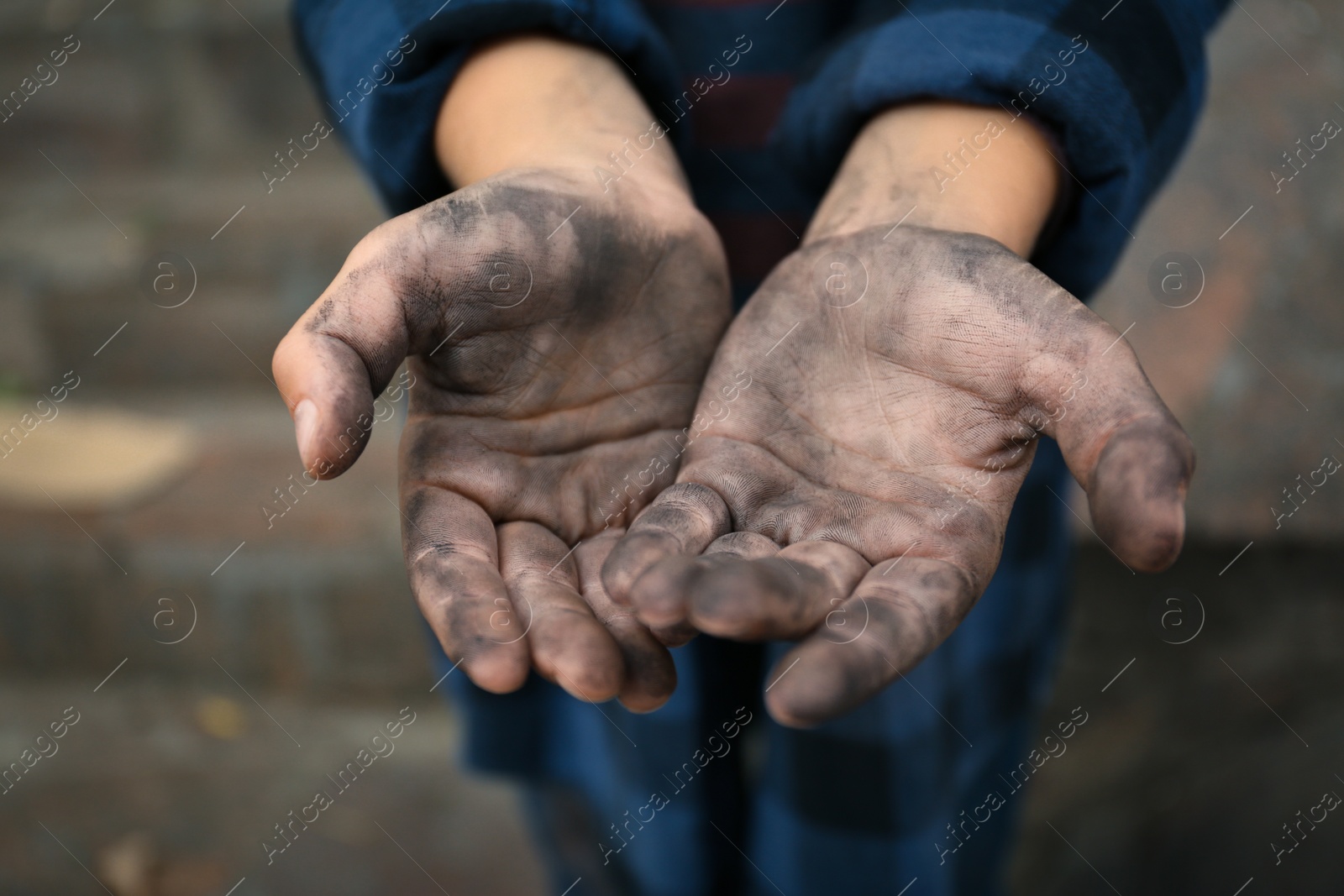 Photo of Poor homeless child begging for help outdoors, closeup