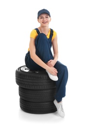 Female mechanic with car tires on white background