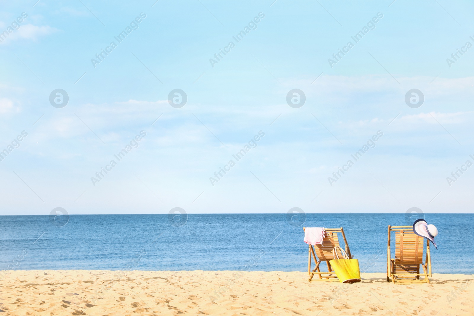 Photo of Empty wooden sunbeds and beach accessories on sandy shore