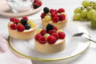 Photo of Delicious tartlets with berries on white wooden table
