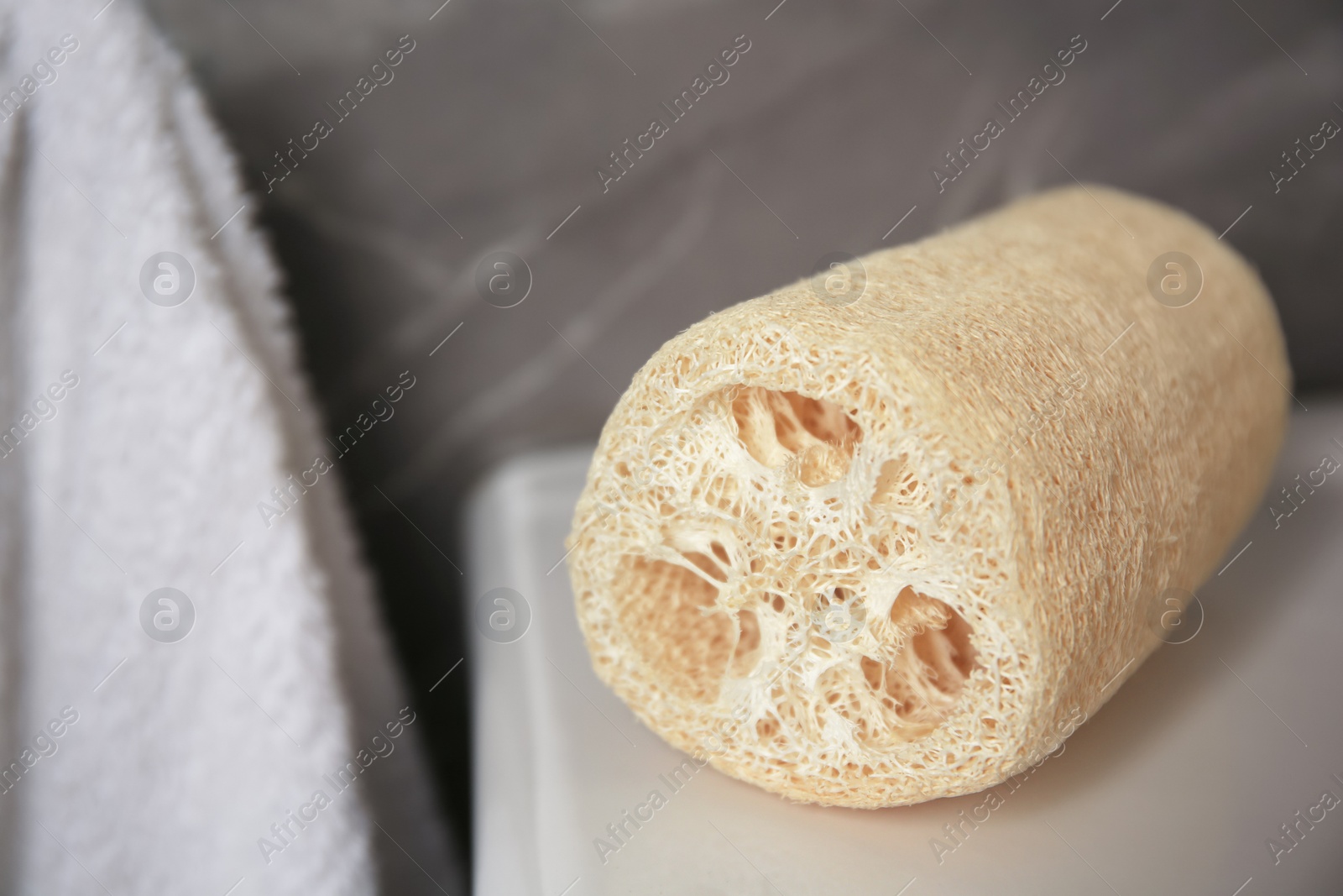 Photo of Natural loofah sponge on washbasin in bathroom, closeup