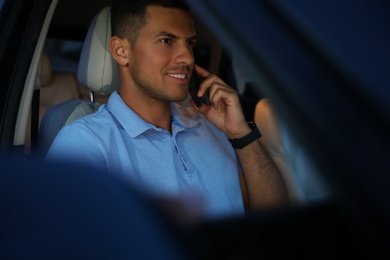 Photo of Handsome man talking on phone in modern car