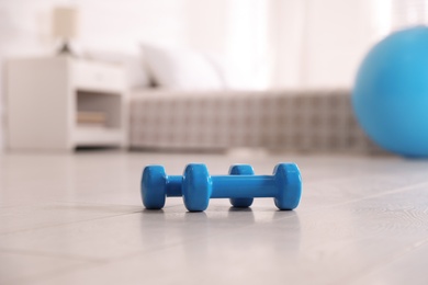 Photo of Blue dumbbells on floor in room. Home fitness