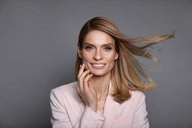 Image of Portrait of stylish attractive woman with blonde hair smiling on grey background