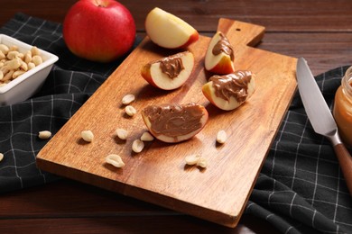 Photo of Slices of fresh apple with nut butter and peanuts on wooden table