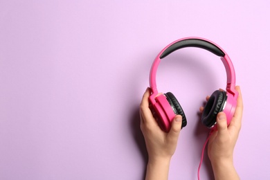 Photo of Woman holding stylish headphones on color background, closeup. Space for text