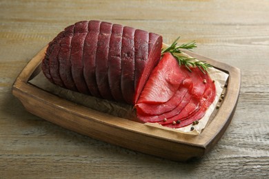 Photo of Tasty bresaola, peppercorns and rosemary on wooden table