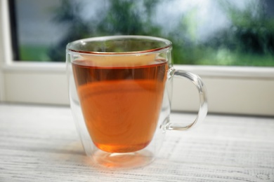 Cup of hot tea on white wooden windowsill