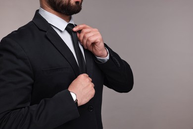 Photo of Businessman in suit and necktie on grey background, closeup. Space for text