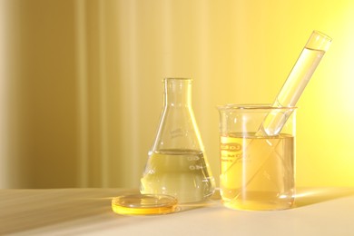Photo of Laboratory analysis. Different glassware on table against light yellow background, space for text