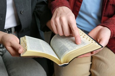 Photo of Humble couple reading Bible together, closeup. Religious literature