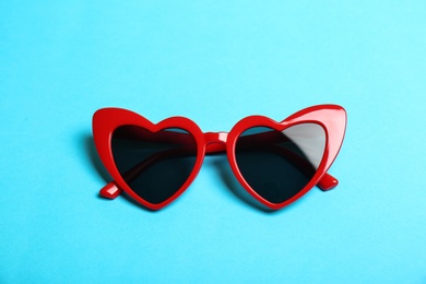 Photo of Red heart shaped sunglasses on color background, top view